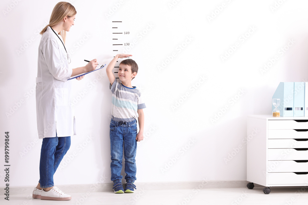 Female doctor measuring height of little boy in clinic Female doctor measuring height of little boy in clinic