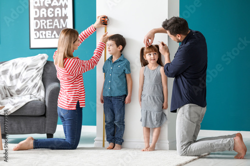Parents measuring height of their children at home photo