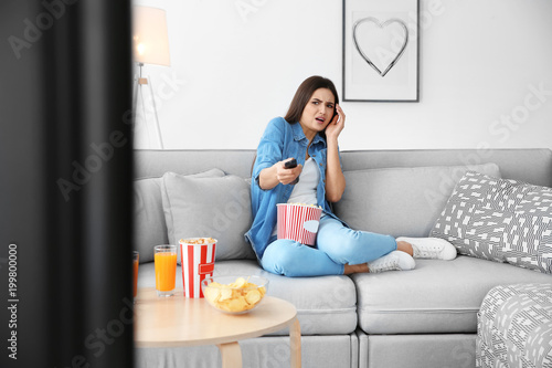 Young woman watching TV on ...