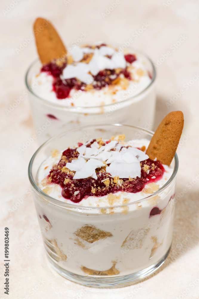 delicious dessert in a glass with cookies, cream and jam, vertical delicious dessert in a glass with cookies, cream and jam, vertical
