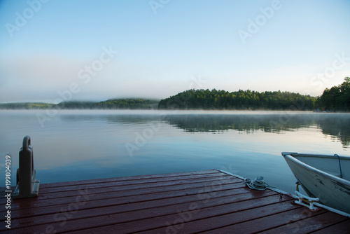 Muskoka dock and boat on a misty morning lake photo