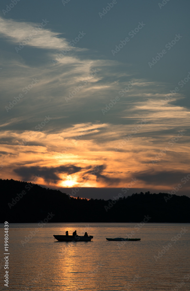 Family fishing on a boat on Ontario lake at sunset