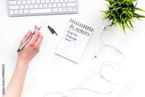 Learn new english vocabulary. Learn landuage concept. Computer keyboard, notebook for writing new vocabulary on white background top view photo