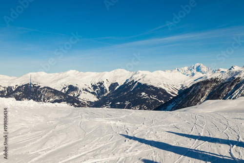 A view of a ski piste in Meribel, in the French Alps. The day is sunny and clear, with a  blue sky. © umike_foto