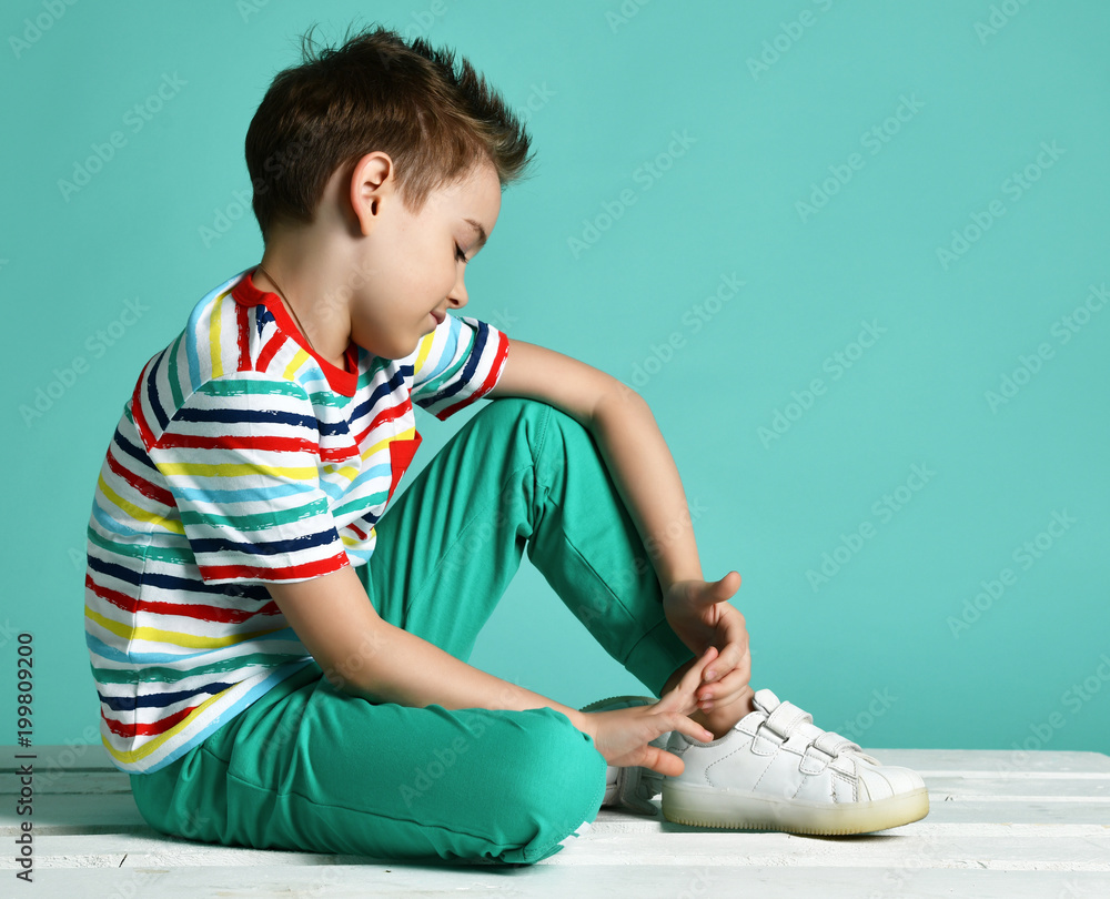 Young boy sitting in stripes casual shirt positive attitude on blue mint background Young boy sitting in stripes casual shirt positive attitude on blue mint background