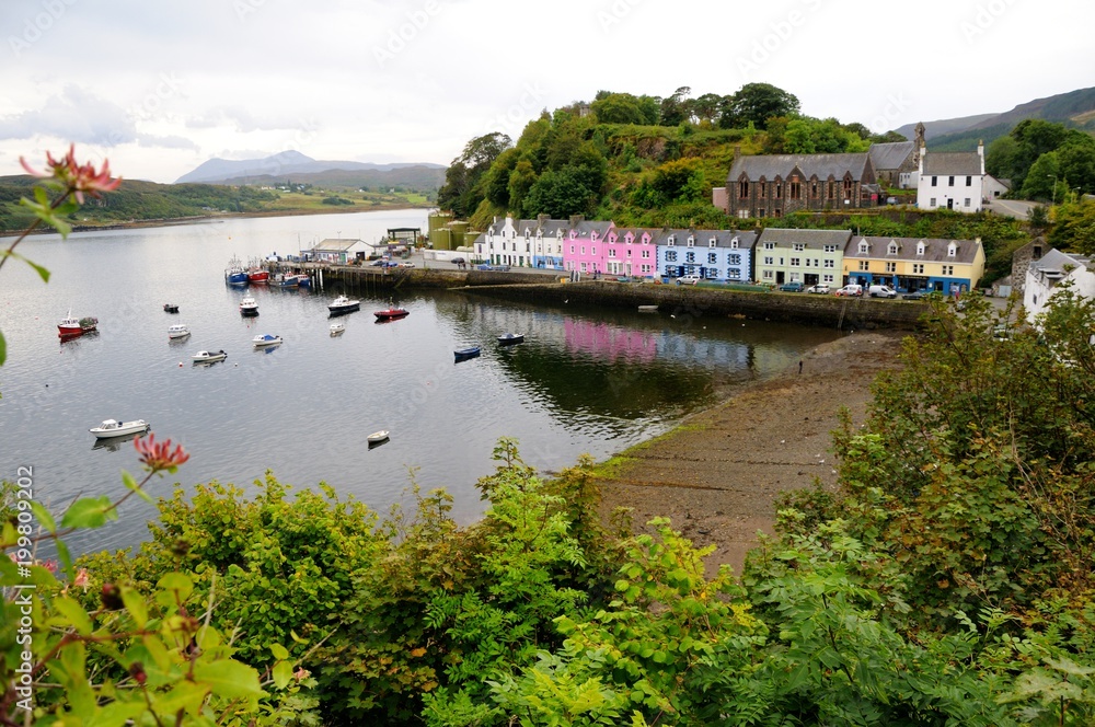 Harbour of Portree with colorful houses and boats in bay, trees in the foreground. Isle of Skye, Scotland.