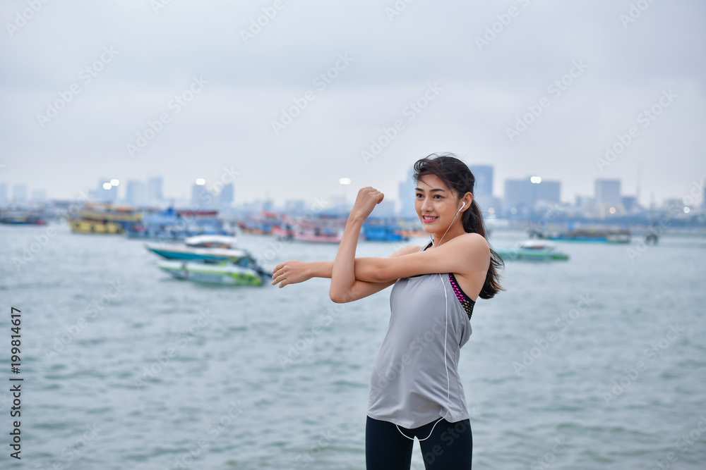 Sports concept. Beautiful girl is exercising on the beach with warm up. Beautiful girl is happy to exercise.