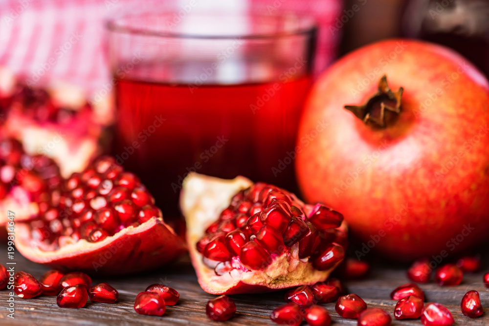 Ripe pomegranates with glass of juice on table Ripe pomegranates with glass of juice on table
