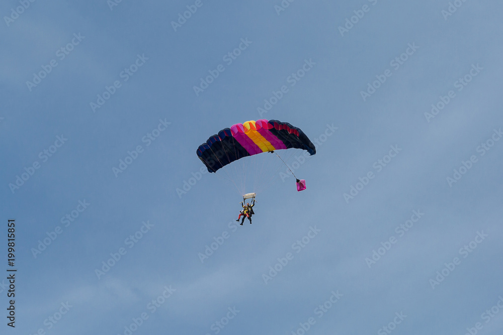 Parachutists: Instructor and Beginner with Blue Parachute against Clear Blue Sky Parachutists: Instructor and Beginner with Blue Parachute against Clear Blue Sky