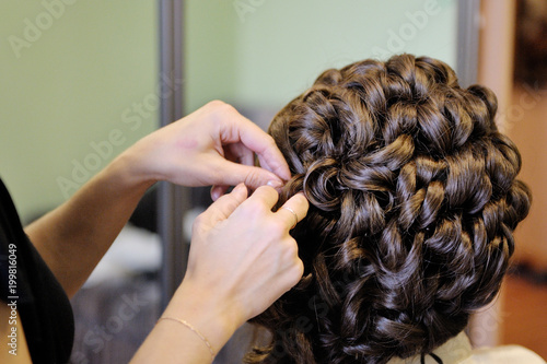 The stylist prepares the bride for the wedding. Hair styling. Morning gathering of the bride.