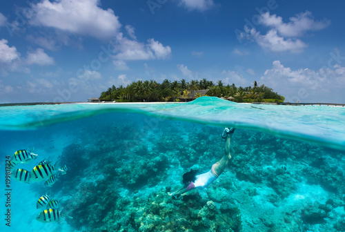 Frau schnorchelt über Korallen und tropischen Fischen vor einer Insel auf den Malediven photo