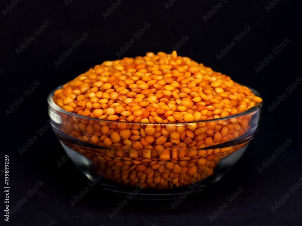 Red raw lentils in a glass bowl. Isolated on black background Red raw lentils in a glass bowl. Isolated on black background