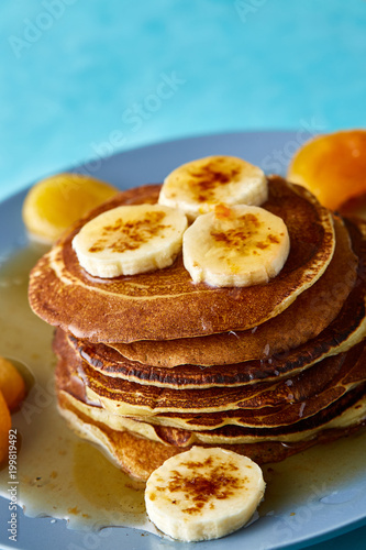 Pile of homemade pancakes with honey and walnuts on rustic wooden background, selective focus