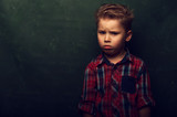 Sad confused little boy stands in dark corner and is afraid of something