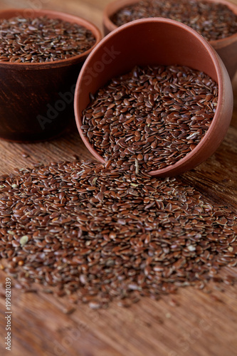 An overturned ceramic bowl with linseeds on a rustic background, close-up, shallow depth of field, selective focus