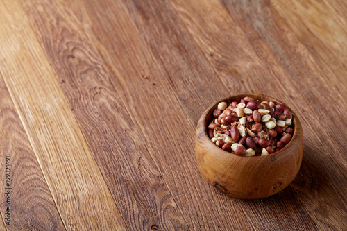 Two ceramic bowls with raw peanuts mix isolated over rustic wooden backround, top view, close-up.