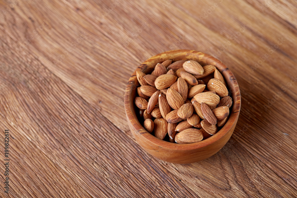 Bowl of almonds on wooden background, top view, close-up, selective focus. Bowl of almonds on wooden background, top view, close-up, selective focus.