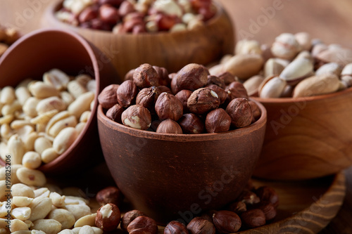 Mixed nuts arrenged on wooden tray over rustic background, close-up, selective focus.