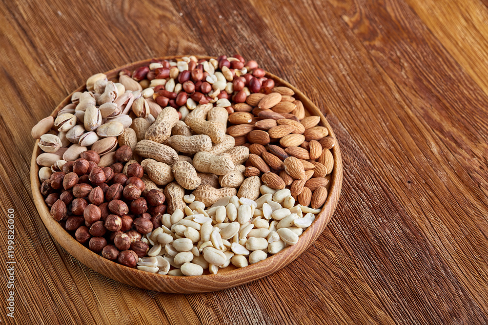 Mixed nuts arrenged on wooden tray over rustic background, close-up, selective focus. Mixed nuts arrenged on wooden tray over rustic background, close-up, selective focus.