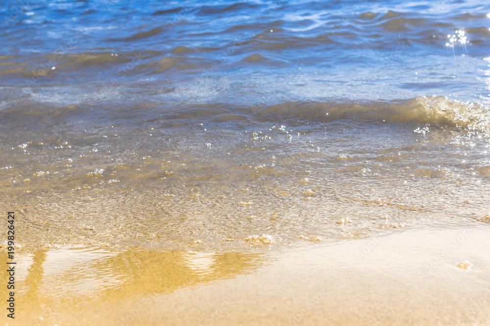 Coast of the sea on a sunny day with blue waves and yellow sand - the concept of relaxation Coast of the sea on a sunny day with blue waves and yellow sand - the concept of relaxation