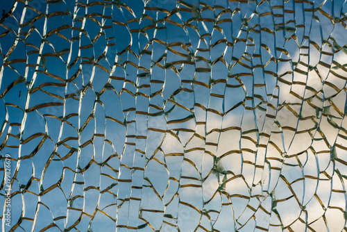 Bright blue sky with clouds through broken glass - beautiful background, texture