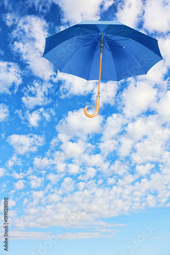 Mary Poppins Umbrella.Blue umbrella flies in sky against of white clouds.