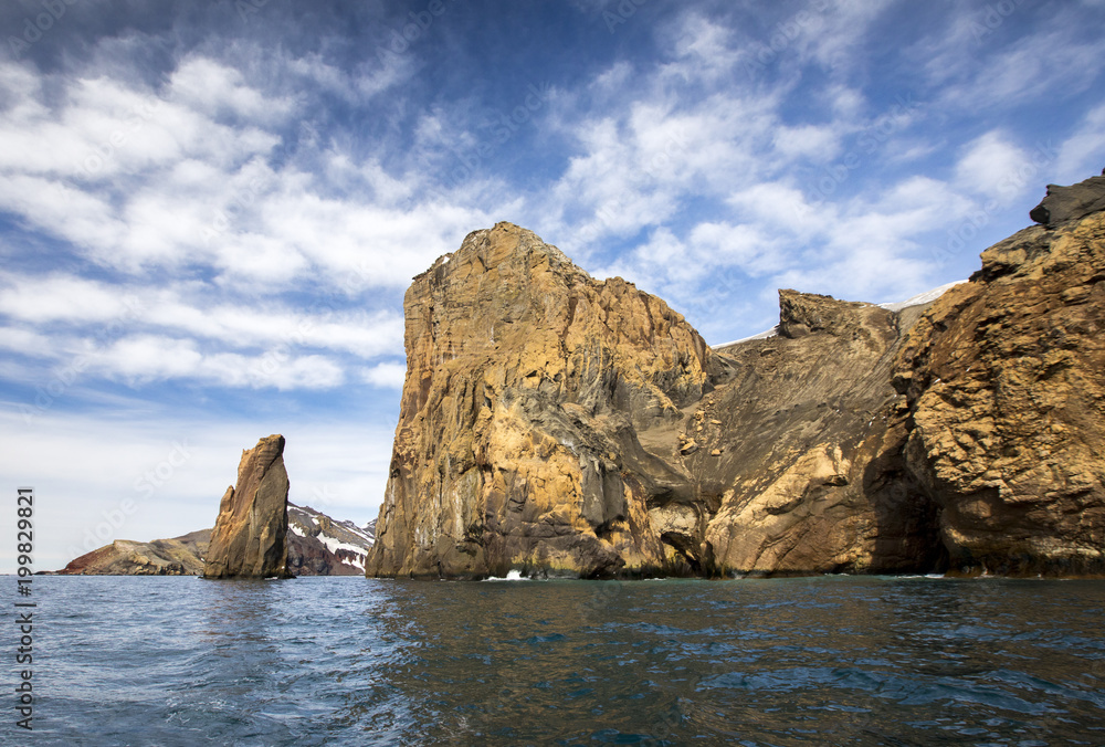 Giant cliffs rise from the ocean on Deception Island in Antarctica, also known as the Land of Fire and Ice because of the combination of glaciers and the active volcano that warms the surroundings. Giant cliffs rise from the ocean on Deception Island in Antarctica, also known as the Land of Fire and Ice because of the combination of glaciers and the active volcano that warms the surroundings.