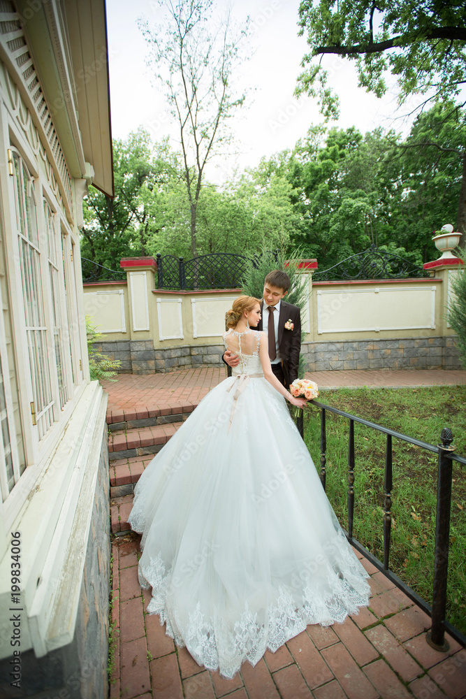 Fototapeta premium beautiful loving young couple groom and bride walking in summer park