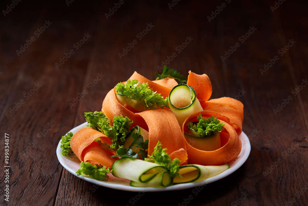 Artistically served vegetable salad with carrot, cucumber, letucce over wooden background, selective focus Artistically served vegetable salad with carrot, cucumber, letucce over wooden background, selective focus