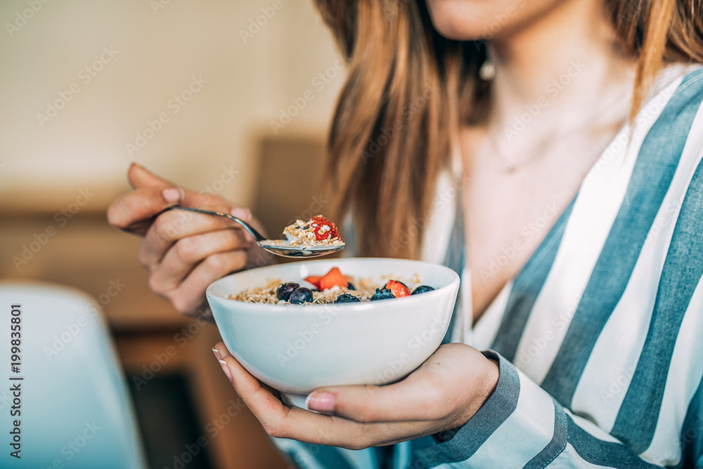Crop woman close up eating oat and fruits bowl for breakfast - obrazy, fototapety, plakaty 