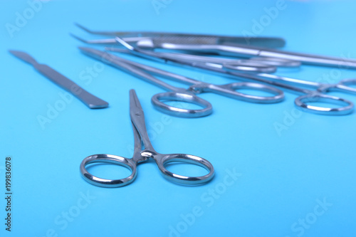 surgical instruments and tools including scalpels, forceps and tweezers arranged on a table for a surgery.
