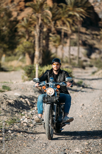Fototapeta Naklejka Na Ścianę i Meble -  young man driving a motorbike in a desert place. lifestyle concept