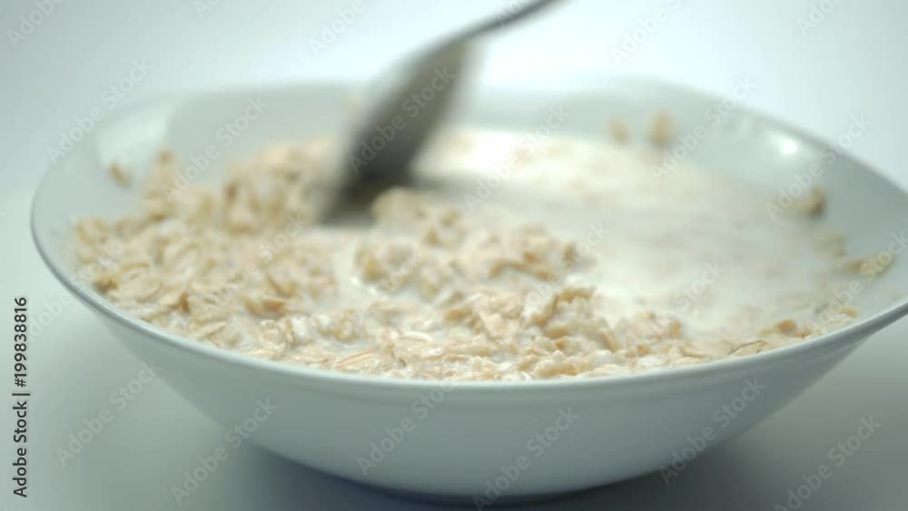 Oat flakes pour milk white bowl closeup slow motion. 4K Oat flakes pour milk white bowl closeup slow motion. 4K
