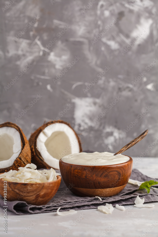 Coconut yogurt in a wooden bowl on a dark background, copy space. Healthy vegan food concept. Coconut yogurt in a wooden bowl on a dark background, copy space. Healthy vegan food concept.