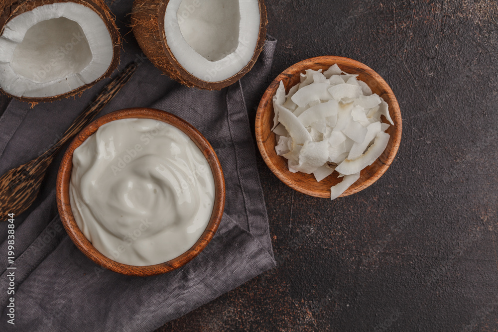Coconut yogurt in a wooden bowl on a dark background, top view, copy space. Healthy vegan food concept. Coconut yogurt in a wooden bowl on a dark background, top view, copy space. Healthy vegan food concept.
