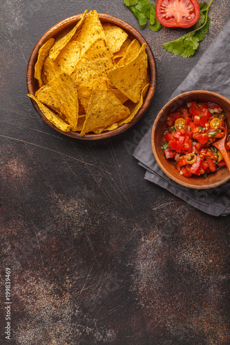 Mexican food concept. Nachos - yellow corn totopos chips with tomato sauce pico del gallo, top view, copy space.