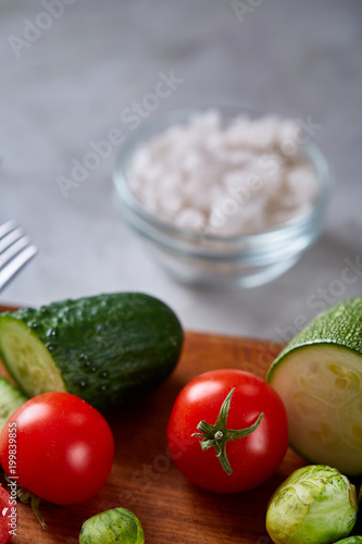 Fresh vegetable salad and ripe veggies on cutting board over white background, close up, selective focus