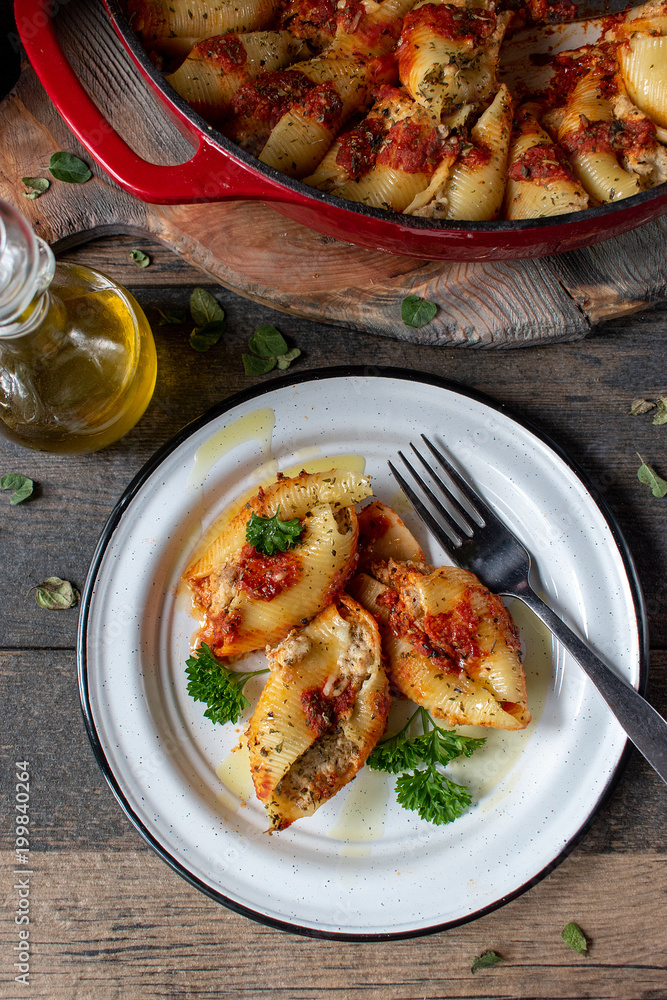 manicotti pasta shells with spinach, ricotta, mozzarella cheese in tomato  sauce on plate in rustic setting flat lay Stock Photo | Adobe Stock