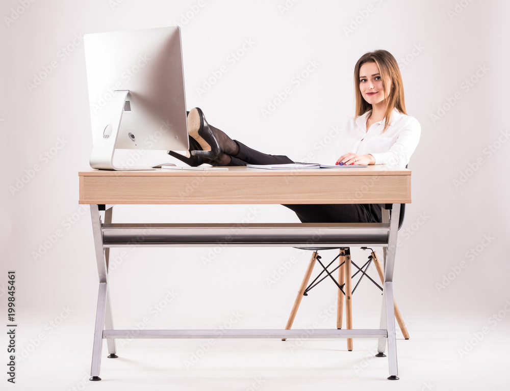 Young attractive successful businesswoman resting her legs on the desk isolated on white