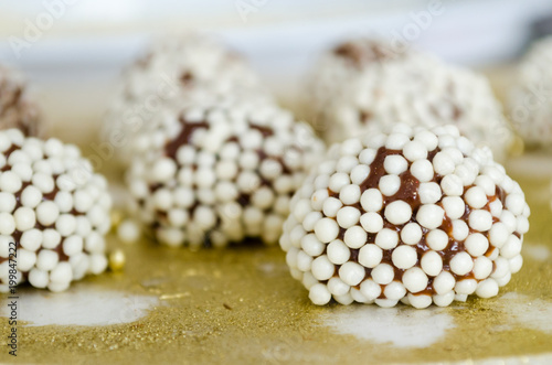 Brigadiers granulated with crunchy white balls on golden tray.