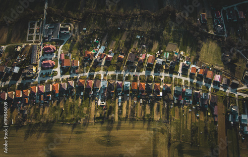 Image of street in (Europe - Slovakia) with a lot of houses in a row in springtime. Street full of houses near the field green meadows and forest. Street from above with stream and many trees.