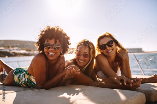 Cheerful women sunbathing on private yacht photo
