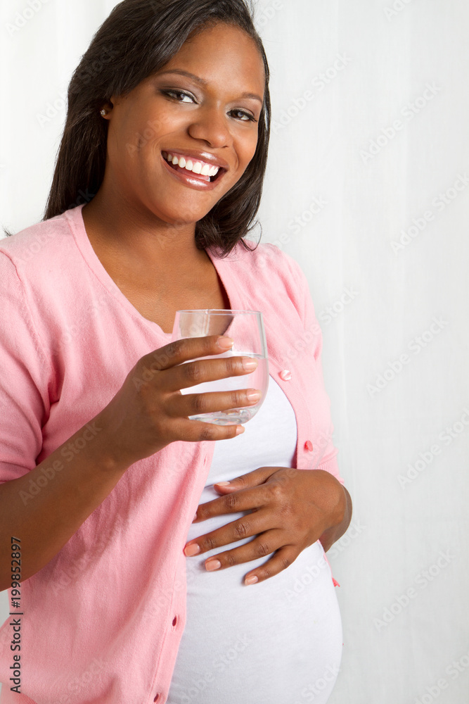 Healthy African American pregnant woman drinking water. Healthy African American pregnant woman drinking water.
