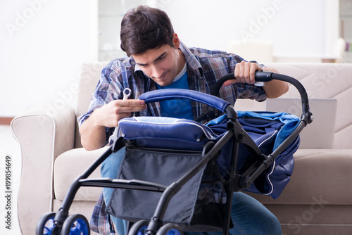 Young father assembling baby pram at home