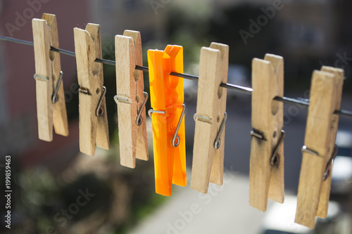 wooden laundry latches on a rope and an orange laundry latch between the latches