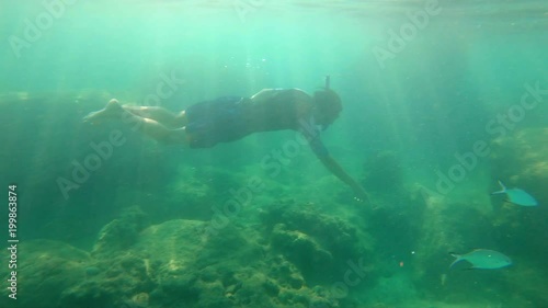 Slowmotion shot of a young man snorkeling and diving dip into sea photo