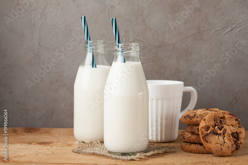 Two bottles of milk and chocolate chip cookies on dark background with copy space photo