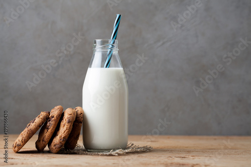 Bottle with milk and chocolate chip cookies on dark background with copy space photo