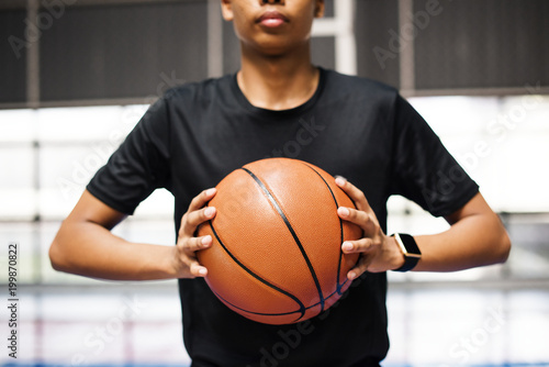African American teenage boy holding a basketball on the court © Rawpixel.com