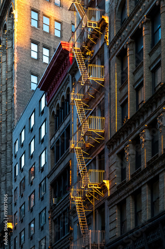 Warm glow of sunlight shining on a fire escape on the front of an old building in New York City